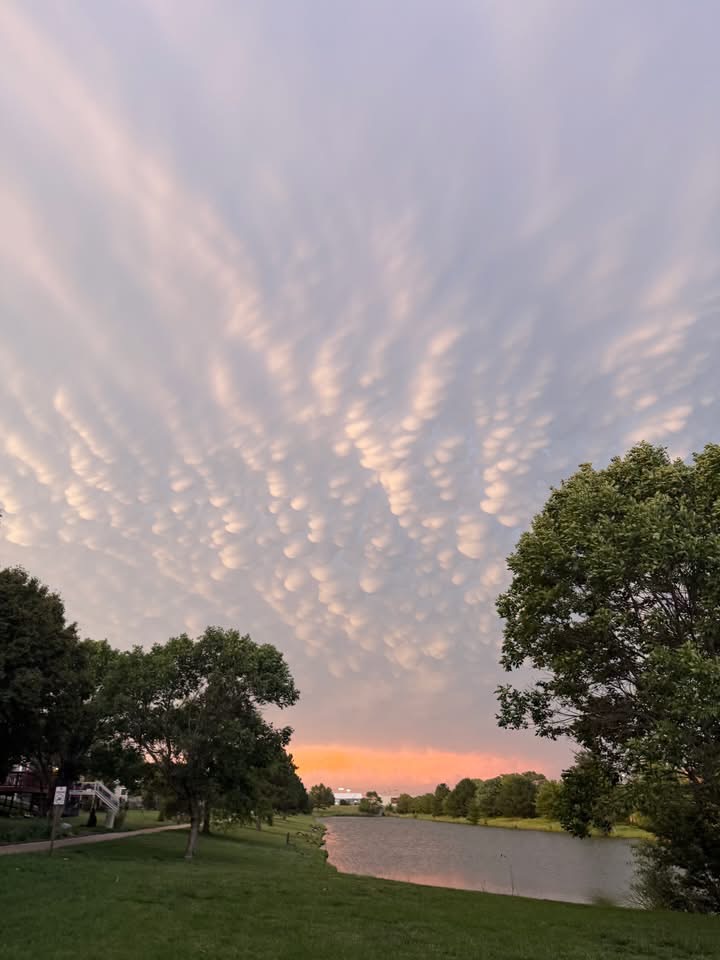 Sunset over the Regency Lakes neighborhood lake, with pink mammatus clouds above the trees and walking path